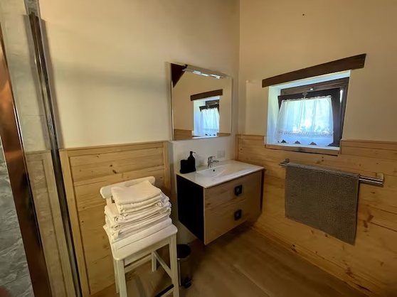 Lavabo del bagno con specchio, finestra e asciugamani