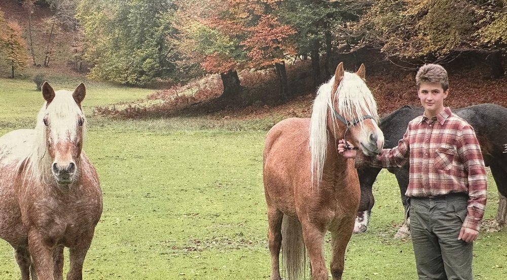 Martino nel prato d'autunno con i cavalli dell'Alpe